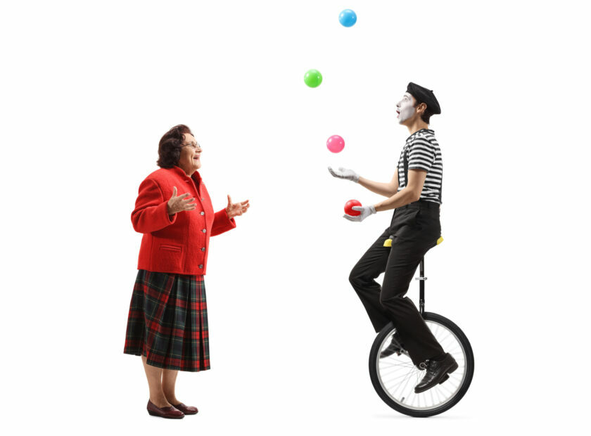 Elderly lady looking at a mime juggling on a unicycle